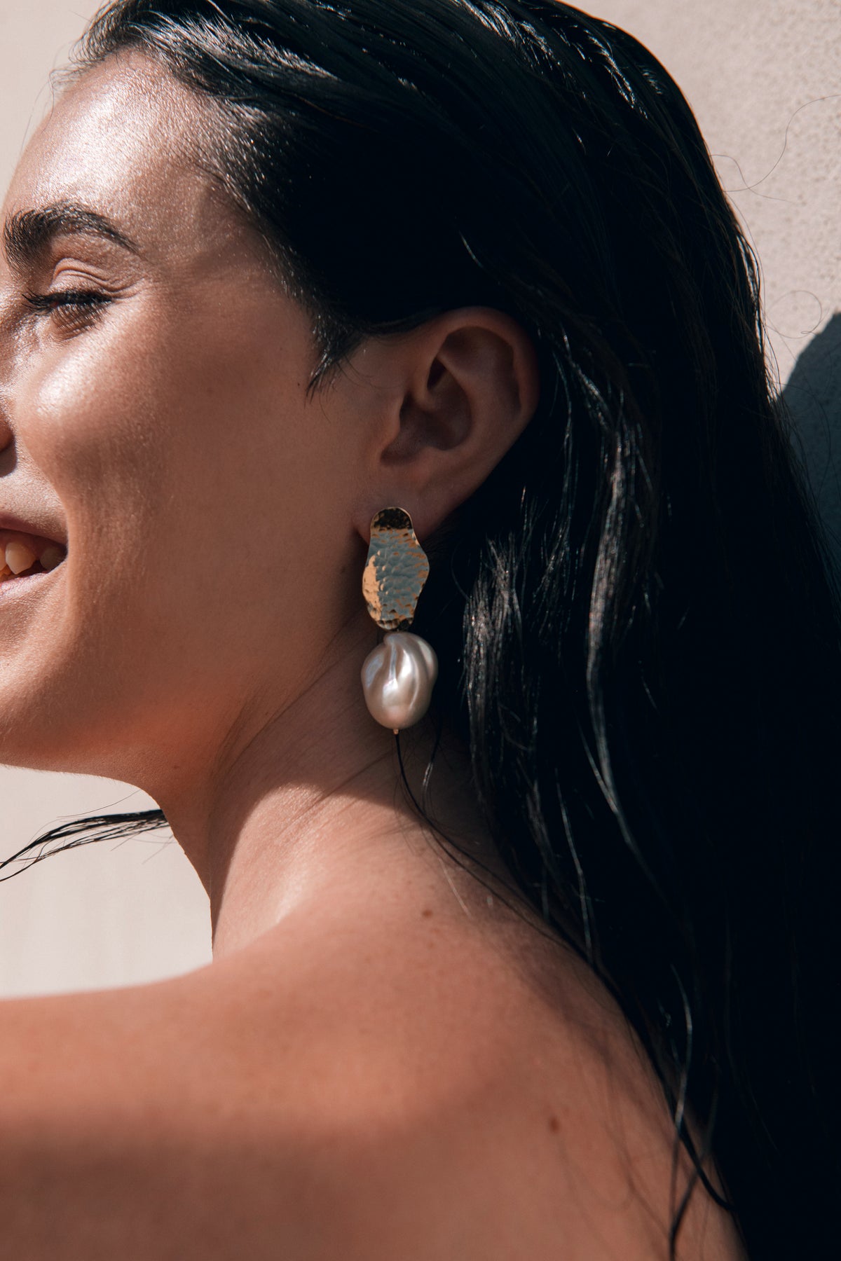 Woman wearing large earrings with a neutral background